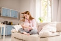 Attractive young girl sitting on couch writing sms on mobile phone. Royalty Free Stock Photo