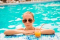 Attractive young girl in spectacles swimming in a pool with orange juice Royalty Free Stock Photo