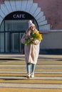 attractive young girl with tulips and a smartphone in her hands crosses the road at a pedestrian crossing. Sunny Weather Royalty Free Stock Photo