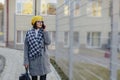 An attractive young girl wearing sunglasses in a coat walking down the street and talking on the phone and smiles Royalty Free Stock Photo