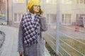 An attractive young girl wearing sunglasses in a coat walking down the street and talking on the phone and smiles Royalty Free Stock Photo