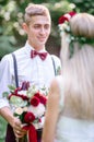 Attractive young groom in blue braces stands before bride Royalty Free Stock Photo