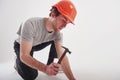 Attractive young guy. Man in casual clothes and orange colored hard hat have some work using hammer. White background Royalty Free Stock Photo