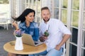 Attractive young guys sit at a table on the terrace in a cafe, enjoy drinks, talk on fun topics. A guy freelancer took a Royalty Free Stock Photo