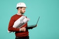 Attractive young handsome bearded engineer or constructor man in casual outfit holding notebook or computer over cyan Royalty Free Stock Photo