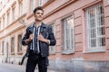 Attractive young hipster man in black jacket. fashionable walks in the city. Urban fresh portrait confident young man