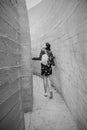 Attractive young woman stands between concrete walls. Caucasian girl in casual jeans and flower dress looks up. Royalty Free Stock Photo