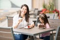 Beautiful Hispanic brunette with daughter at cafe Royalty Free Stock Photo