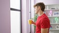 Attractive young hispanic man deeply absorbed in thought, casually sipping his morning coffee, looking through the living room Royalty Free Stock Photo