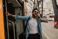 Attractive young hispanic wearing sunglasses and blue shirt male holding smartphone hand and calling to friends while he