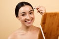 Attractive young indian woman correcting shape of eyebrows with tweezers Royalty Free Stock Photo