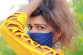 An attractive young Indian woman poses in nature wearing a face mask to avoid a life-threatening illness such as Corona