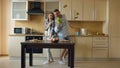 Attractive young joyful couple have fun dancing and singing while cooking in the kitchen at home Royalty Free Stock Photo