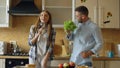 Attractive young joyful couple have fun dancing and singing while cooking in the kitchen at home Royalty Free Stock Photo