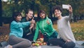 Attractive young ladies yogini are taking selfie using smartphone during picnic in park in autumn. Girls are posing and