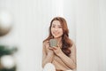 Attractive young lady with cup sitting on window sill at home Royalty Free Stock Photo