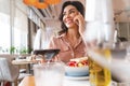 Attractive young lady having phone conversation in cafe Royalty Free Stock Photo