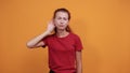 Attractive young lady in red shirt keeping hand on ears, gossip