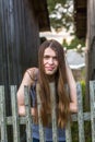 Attractive young with long hair woman standing near a wooden fence. Royalty Free Stock Photo