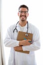 Attractive young male doctor with stethoscope over neck holding clipboard isolated on white. Royalty Free Stock Photo