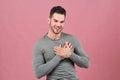 Attractive young man of athletic build smiles happily and holds his hands near his heart. The concept of love, fun and intimacy. Royalty Free Stock Photo