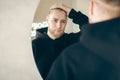 An attractive young man with a beard looks at himself in the mirror. Royalty Free Stock Photo
