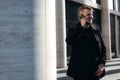 Attractive young man in black turtleneck and coat smiling talking on the phone on the street Royalty Free Stock Photo