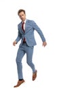 Attractive young man in blue suit jumping in the air Royalty Free Stock Photo