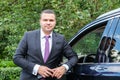 Attractive young man in a business suit and tie stands next to his car. Portrait of a successful businessman Royalty Free Stock Photo