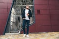 Attractive young man in casual clothers with coffee in his hands standing on office building background. Royalty Free Stock Photo