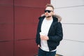 Attractive young man in casual clothers with coffee in his hands standing on office building background. Royalty Free Stock Photo