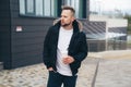 Attractive young man in casual clothers with coffee in his hands standing on office building background. Royalty Free Stock Photo