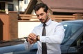 Attractive young man checking time near  car outdoors Royalty Free Stock Photo