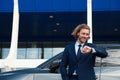 Attractive young man checking time near luxury car Royalty Free Stock Photo