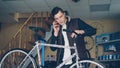 Attractive young man cheerful mechanic is talking on mobile phone and assembling bicycle handle-bar. People, maintenance Royalty Free Stock Photo