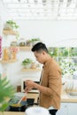 Attractive young man is cooking on kitchen with laptop on table while talking on smart phone Royalty Free Stock Photo