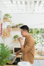 Attractive young man is cooking on kitchen with laptop on table while talking on smart phone Royalty Free Stock Photo