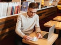 Attractive young man drinking coffee and using laptop. Royalty Free Stock Photo