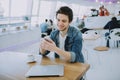 Attractive young man or freelancer with mobile is sitting in cafe and drinking coffee Royalty Free Stock Photo