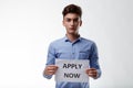 Attractive young man holding a sign with text - Apply Now