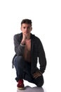 Attractive young man kneeling with sweater on naked torso