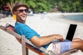 Attractive young man with laptop working on the beach. Freedom,