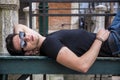 Attractive young man laying down on wood bench
