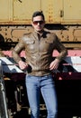 Attractive young man in leather jacket and jeans in front of old train Royalty Free Stock Photo