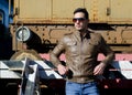 Attractive young man in leather jacket and jeans in front of old train Royalty Free Stock Photo