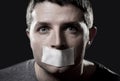 Attractive young man with mouth sealed on duct tape to prevent him from speaking Royalty Free Stock Photo