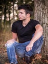 Attractive young man in park resting against tree Royalty Free Stock Photo