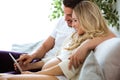 Attractive young man and pregnant woman lying on sofa and using digital tablet to looking ultrasound scan of baby at home Royalty Free Stock Photo