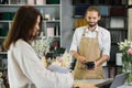 Attractive young man receives payment for a bouquet of flowers with credit card in flower shop Royalty Free Stock Photo