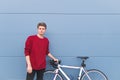 Attractive young man in a red sweatshirt stands with a white blooming on the background of a blue wall Royalty Free Stock Photo